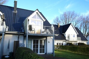 A two-story house with a balcony, a covered patio, and a well-maintained garden. - Ferienwohnung mit 3- Zimmern auf ca. 100 m² (Wyk auf Föhr)