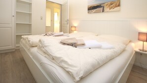 Una cama bien hecha con toallas, una lámpara de noche y un cuadro en la pared.