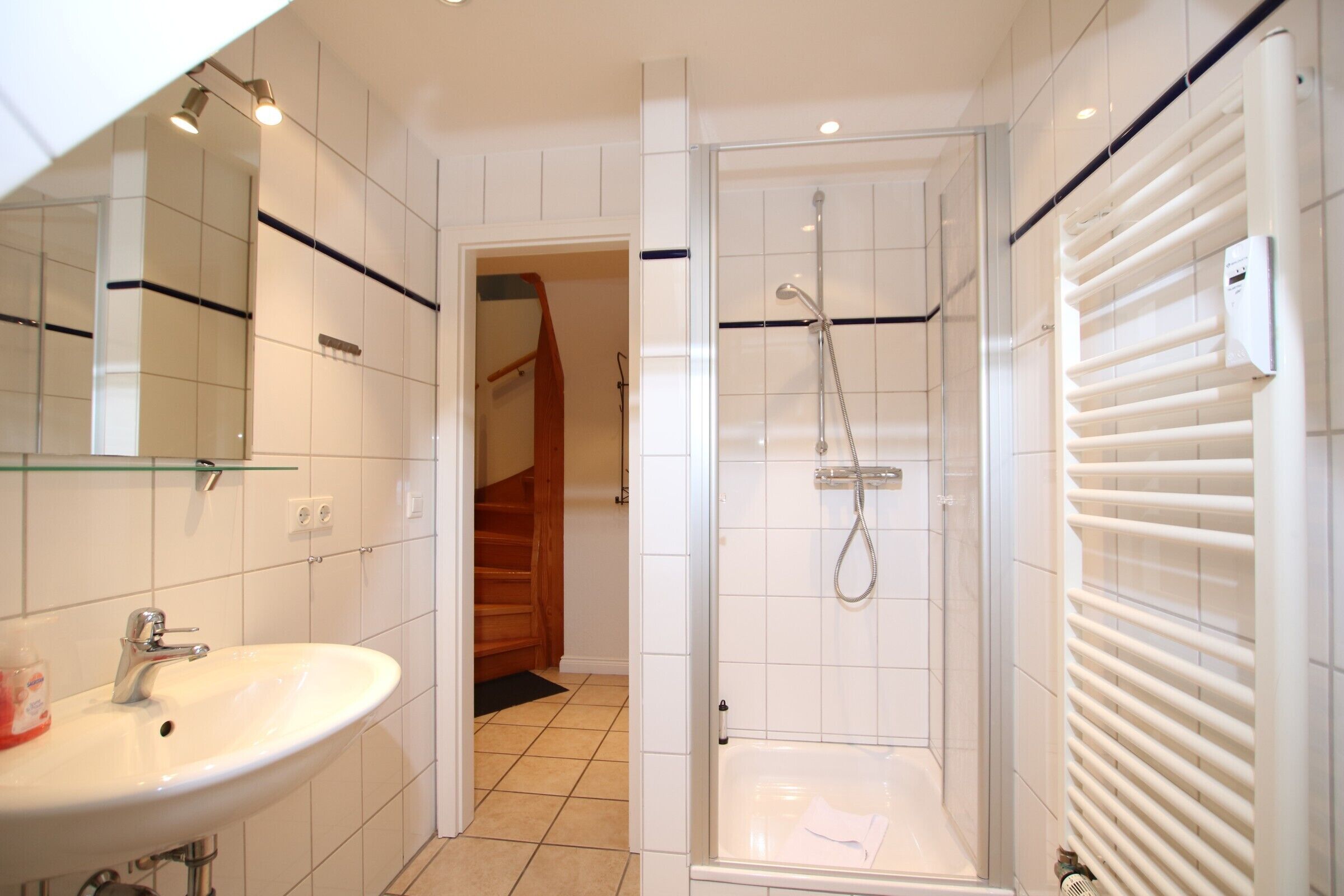 Un baño moderno con ducha acristalada, lavabo y espejo.