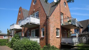 Ein zweistöckiges Backsteingebäude mit einem markanten dreieckigen Dach und einem Balkon in jeder Etage.