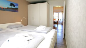 A hotel room with two beds, a wardrobe, and a painting on the wall. - Ferienwohnung mit 3- Zimmern auf ca. 50m² (Wyk auf Föhr)