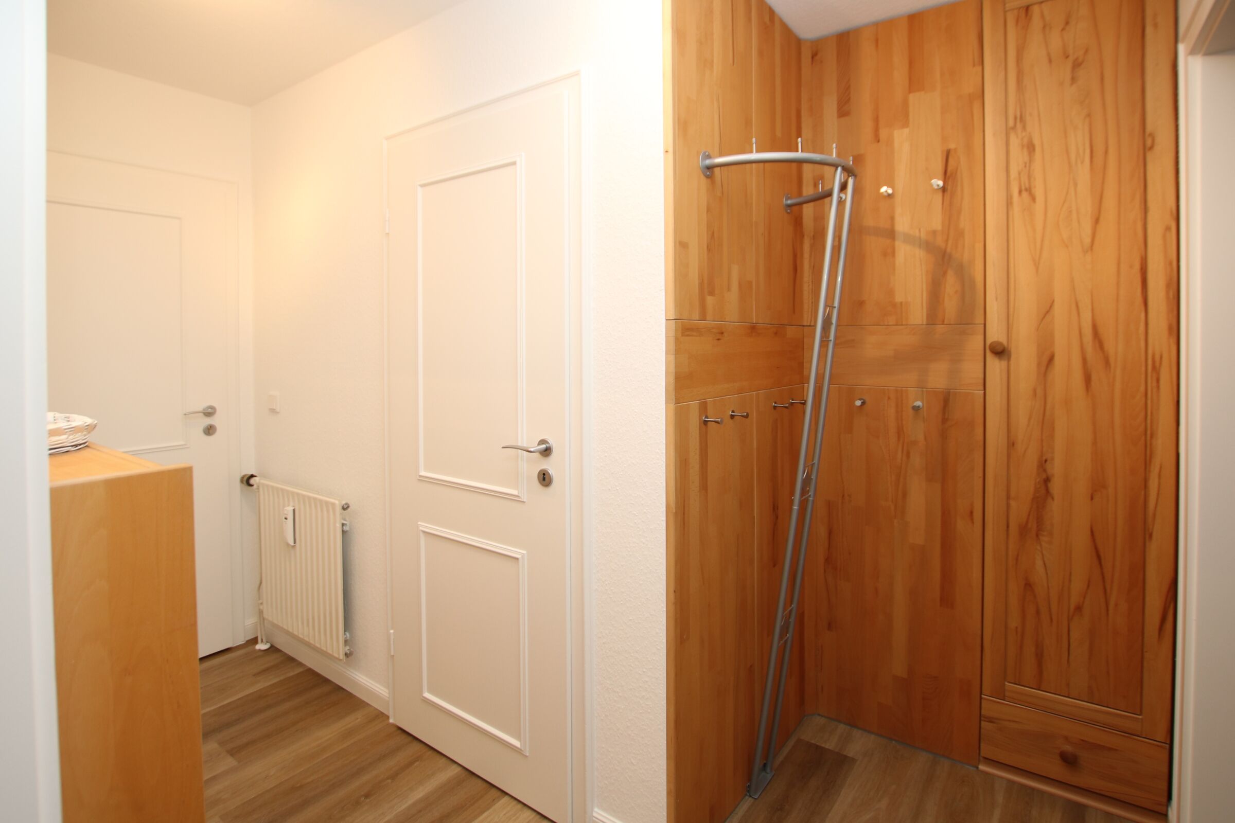 A hallway with wooden doors, a radiator, and a metal ladder leaning against a wooden wall.