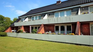 Ein zweistöckiges Wohngebäude mit Flachdach, großen Fenstern und einem Balkon mit Blumenkästen.