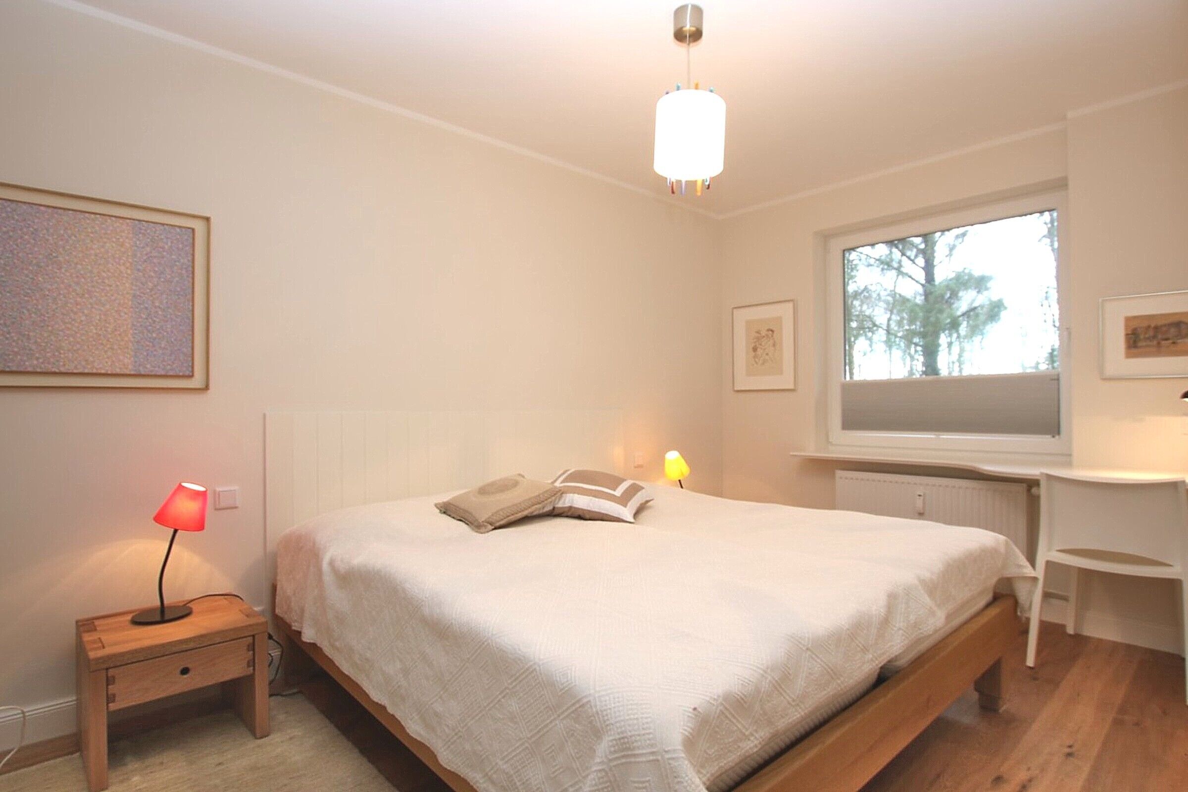 Une chambre à coucher avec un lit, des lampes de chevet, une fenêtre et un bureau.