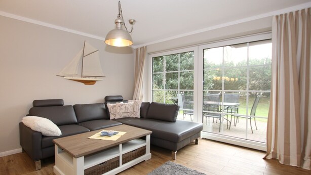 A modern living room with a grey sectional sofa, a wooden coffee table, and a sailboat decoration. - Ferienwohnung mit 3 Zimmern, Sehr Komfortabel und Komplett Renoviert auf 58 m² (Wyk auf Föhr)