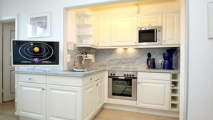 Een moderne keuken met witte kasten, een ingebouwde oven, een magnetron en een koffiezetapparaat.