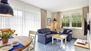 Una habitación con una mesa de comedor, dos sofás, una mesa de centro y una lámpara.