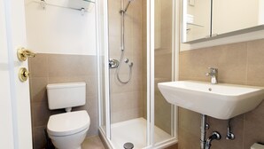 Un baño moderno con inodoro, ducha envuelta en cristal y lavabo.