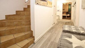 Un escalier menant à une pièce où se trouvent un lit et un tableau accroché au mur.