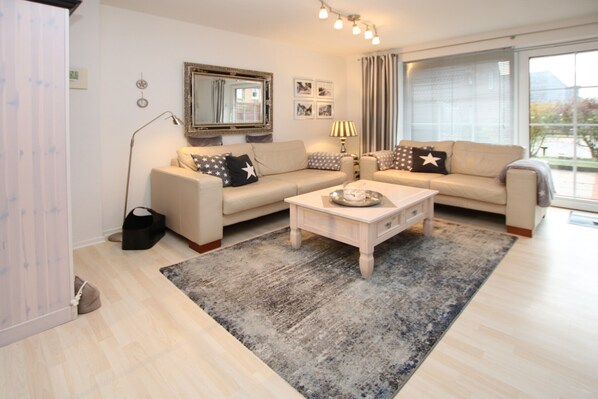 Un salon moderne avec un ensemble de canapés, une table basse et une grande fenêtre agrémentée de rideaux.