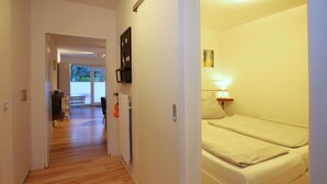 Ein Hotelzimmer mit Bett, Nachttisch, Lampe und Blick ins Freie.