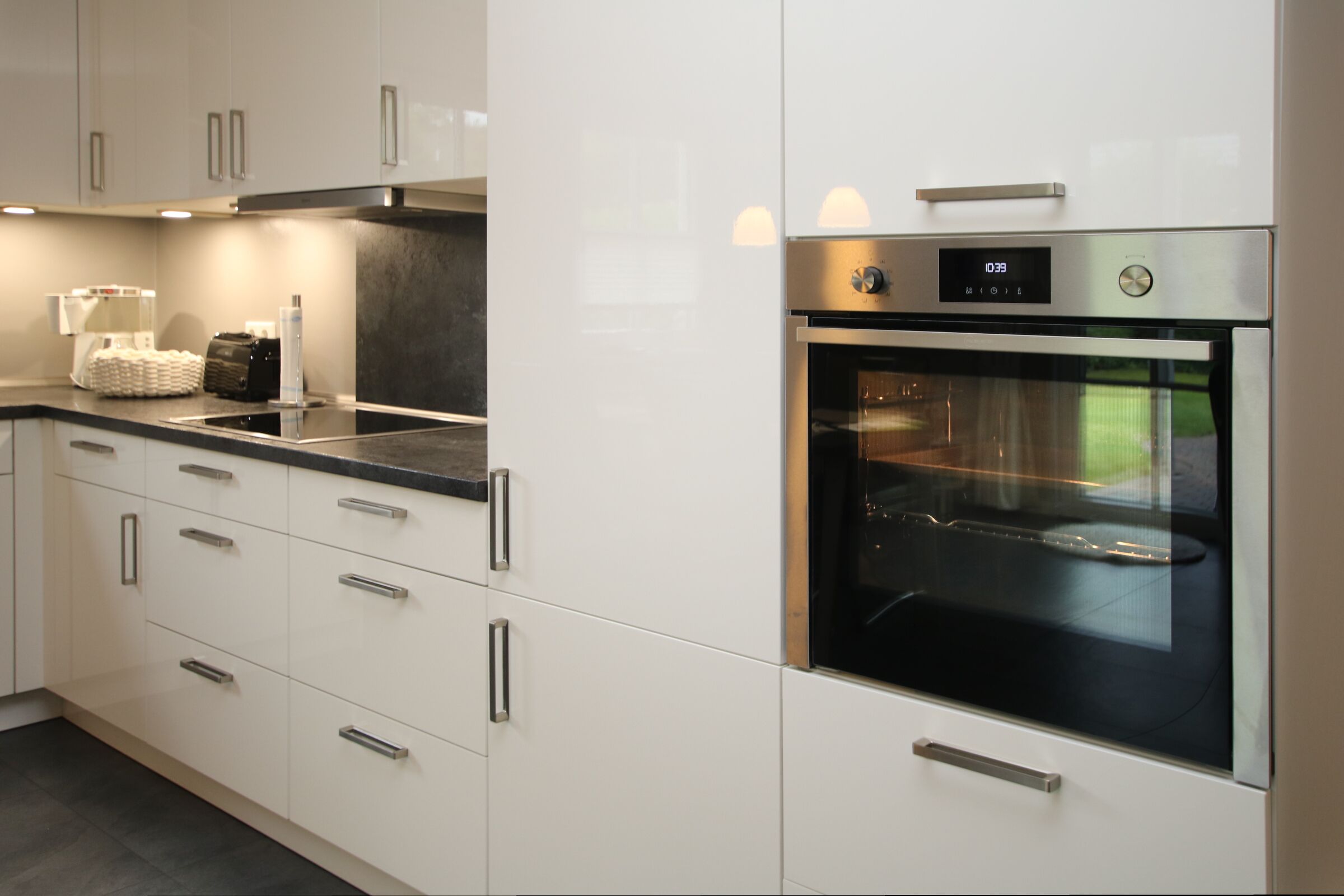 Een moderne keuken met roestvrijstalen apparatuur, witte kasten en een zwart aanrecht.