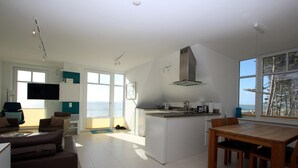 Una sala de estar moderna con un sofá y una mesa de centro, una cocina con una isla grande y un comedor con una mesa de madera.