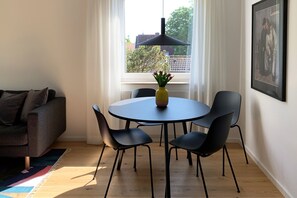 A dining area with a round table, four chairs, a vase with flowers, and a pendant light. - Ferienwohnung mit 3 - Zimmern auf ca. 50m² (Wyk auf Föhr)