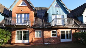 A two-story house with a brick facade, white-framed windows, and a blue exterior.