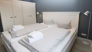Habitación de hotel con cama doble, una cama individual, armario y lámpara de noche.