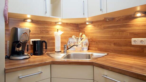 Una cocina moderna con encimeras de madera, un lavaplatos integrado y electrodomésticos de acero inoxidable.