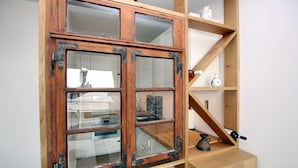 Ein Holzschrank mit Glastüren, ein Regal mit Dekorationsobjekten und eine Weinflasche.