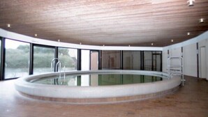 Ein großes Hallenbad mit Holzbalkendecke und Glaswänden.