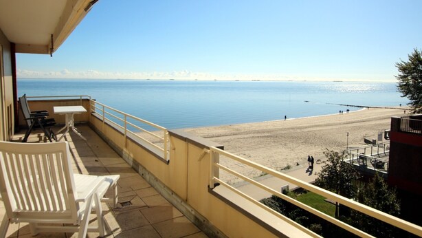 Ein Balkon mit Blick auf Strand und Meer.