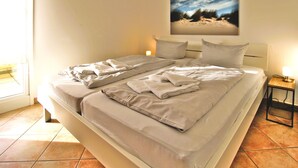 Ein ordentlich bezogenes Doppelbett mit Kissen, eine Nachttischlampe und ein Gemälde an der Wand.