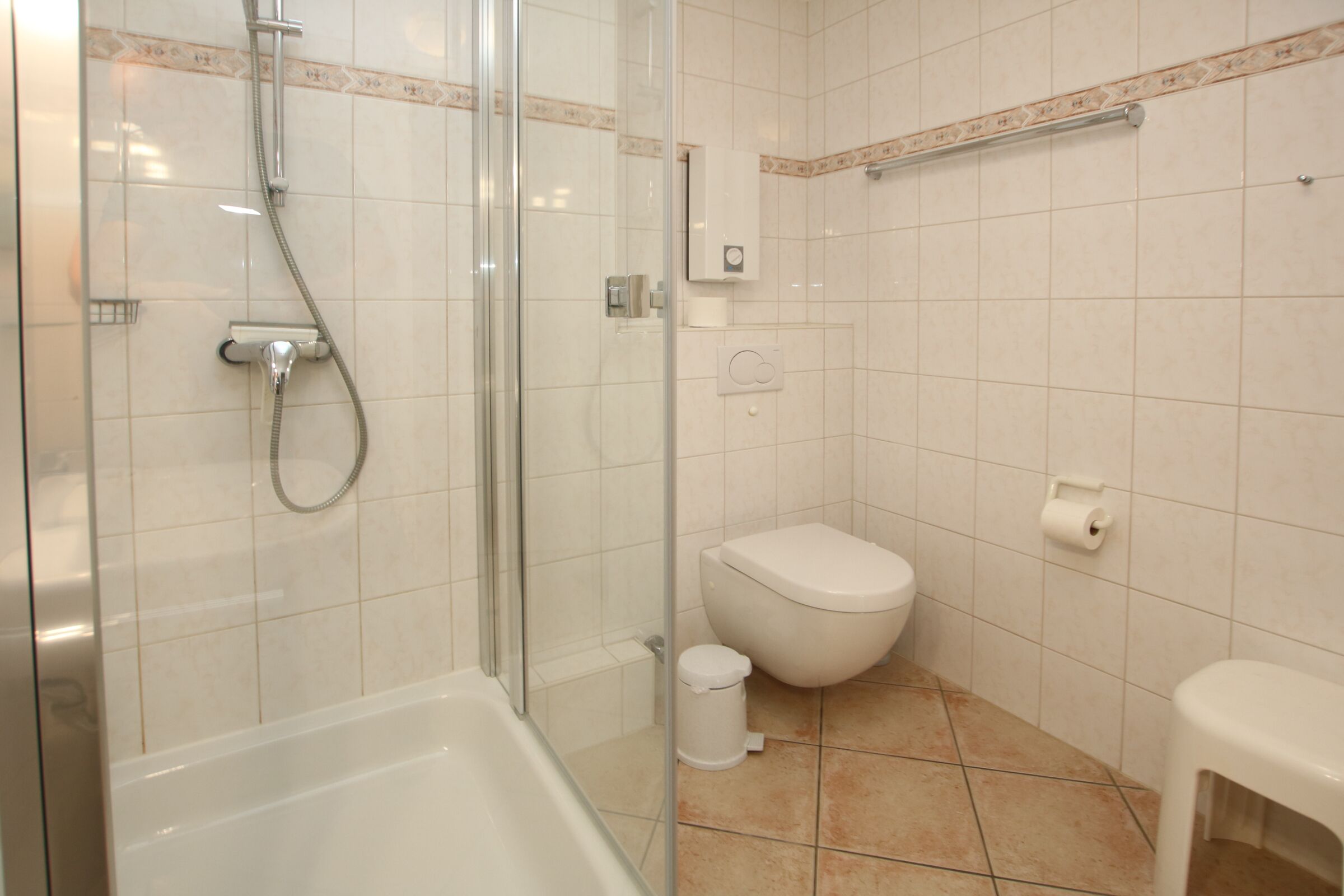 A modern bathroom with a glass-enclosed shower, a white toilet, and a bathtub.