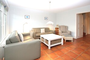 Un salon comprenant un canapé, un fauteuil, une table basse et une chaise en osier.