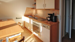 Uma cozinha com armários de madeira, uma pia, um fogão e uma cafeteira.