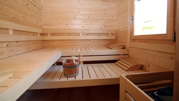 Een sauna met houten banken en een houten emmer.