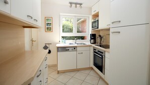 Een moderne keuken met witte kasten, een vaatwasser, een oven en een magnetron.