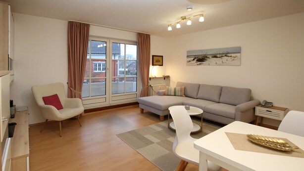 A modern living room with a sofa, armchair, and dining table. - Ferienwohnung mit 2-zimmern mit ca. 45m² und Balkon (Wyk auf Föhr)