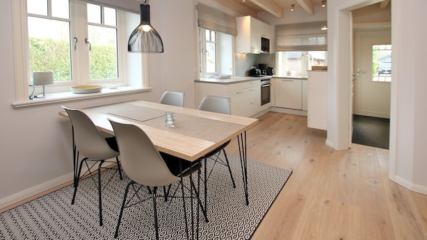 Una cocina moderna con una mesa de comedor de madera, sillas y un tapete estampado.
