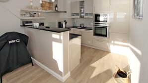 Una cocina moderna con armarios blancos, microondas integrado y cafetera.