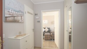 Un pasillo que conduce a un dormitorio con una cama, un aparador y un cuadro de pájaros en la pared.