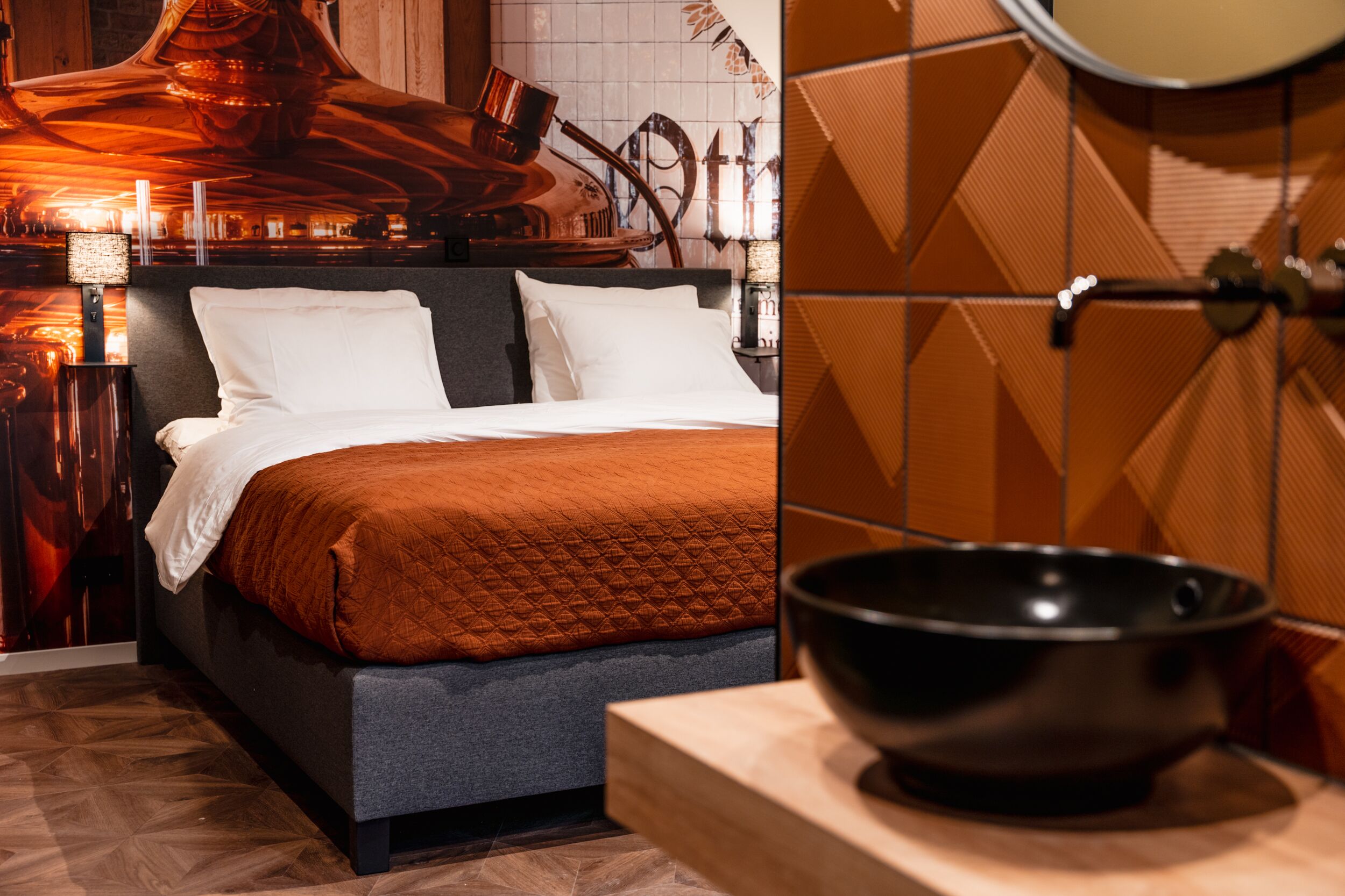 A modern hotel room with a large bed, a wooden nightstand, and a black bowl on a wooden tray.