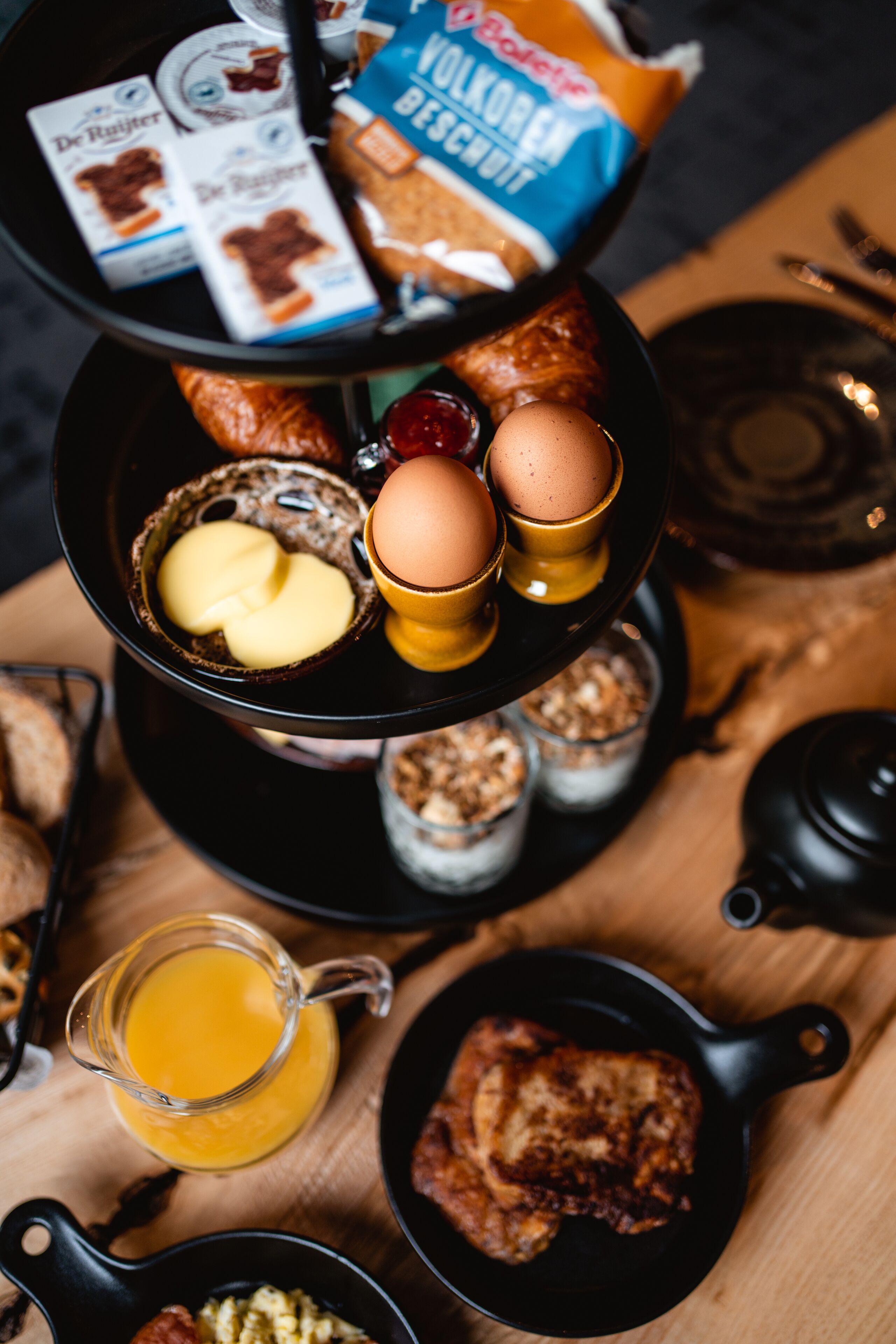 A breakfast tray with eggs, butter, jam, and bread.