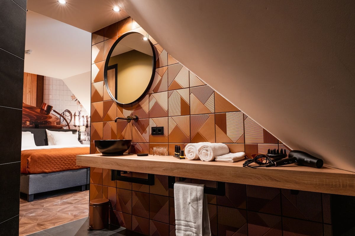 Une salle de bain moderne avec un meuble-lavabo en bois, un miroir rond et un porte-serviettes.