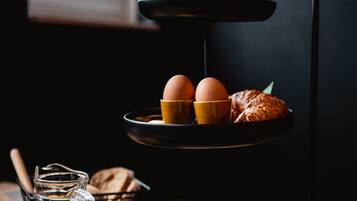 A breakfast setup with eggs, croissants, and a teapot on a tiered stand.