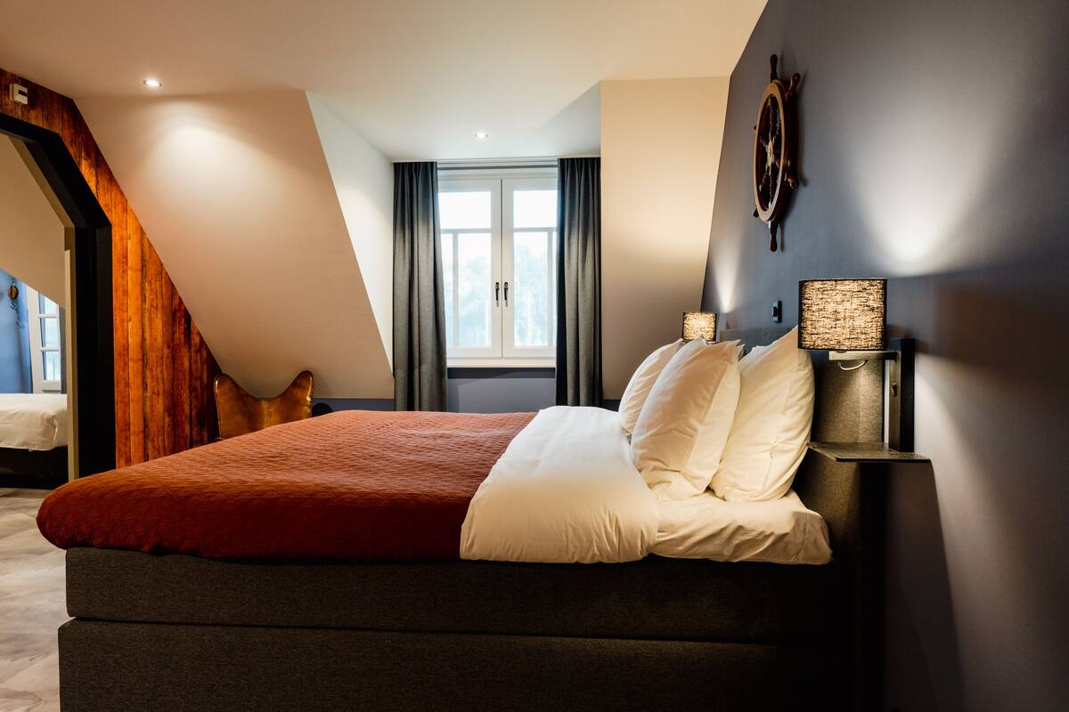 Une chambre moderne avec un grand lit, un escalier en bois et une vue sur l’extérieur.