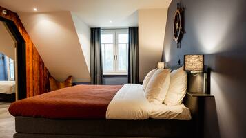 A modern bedroom with a large bed, a wooden staircase, and a view of the outdoors.