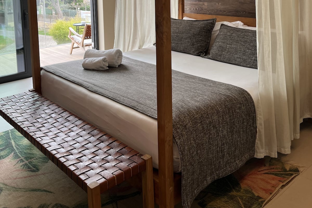 Een hemelbed met een bankje, een groot raam en uitzicht op de omgeving.
