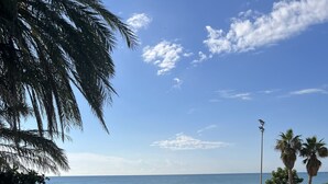 Un espace piscine avec des chaises longues et des parasols, une vue sur la plage et des palmiers.
