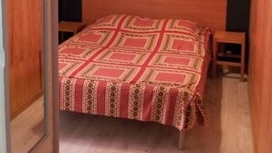 A bedroom with a wooden sloped ceiling, a bed with a patterned bedspread, a nightstand, and a small table. - Villa des Familles - Antarès - Peace and quiet at La Bourboule (La Bourboule)