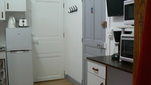A compact kitchen with a white refrigerator, a microwave, and a coffee maker on the counter. - Villa des Familles - Antarès - Peace and quiet at La Bourboule (La Bourboule)