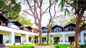 A courtyard with multiple buildings, a central lawn, and surrounding trees. - JP Resort (Arambol)