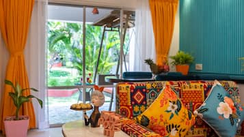 Una habitación con un sofá de colores, una mesita pequeña y una planta en maceta.
