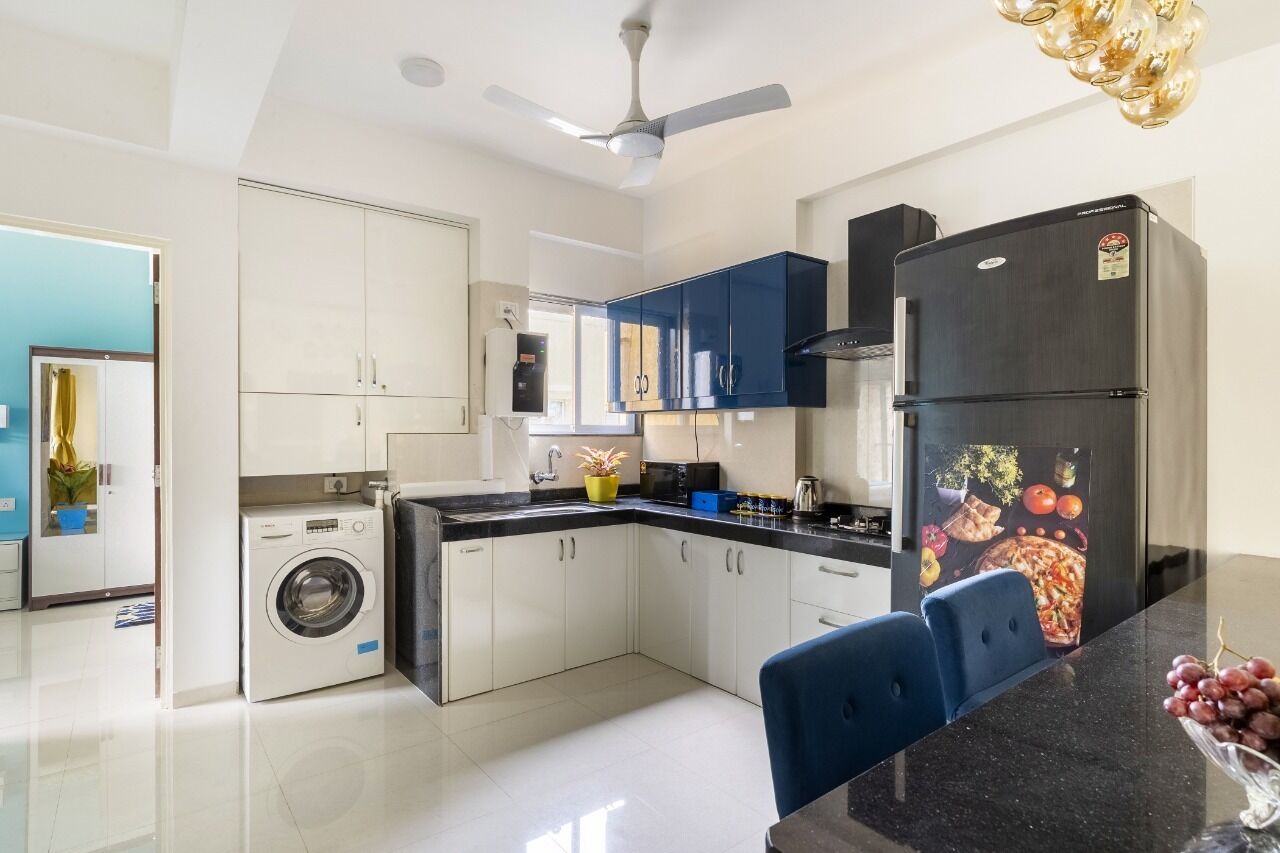 Een moderne keuken met een wasmachine, een koelkast en een eethoek met stoelen.