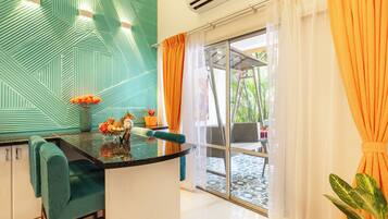 Une cuisine moderne avec un revêtement mural turquoise, un îlot central agrémenté d’un vase de fleurs et un coin repas avec des chaises turquoise.