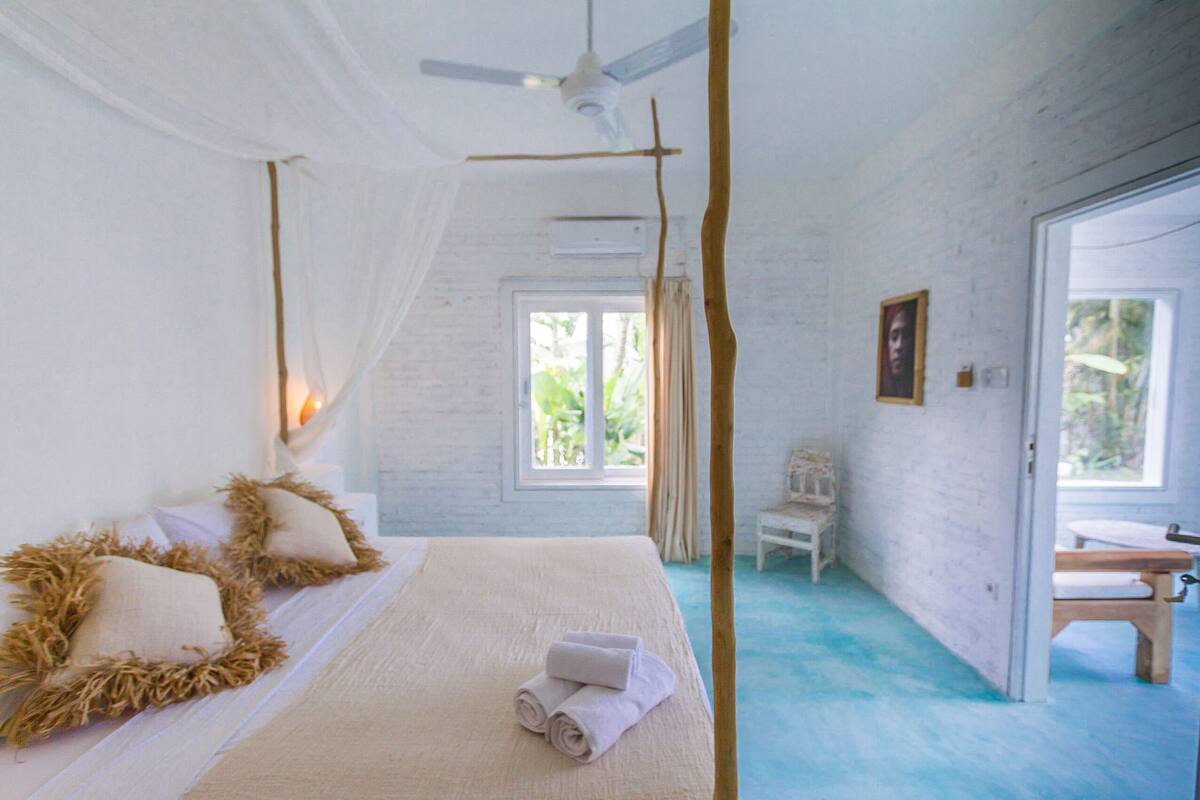 A bedroom with a bed, a ceiling fan, a window, and a door.