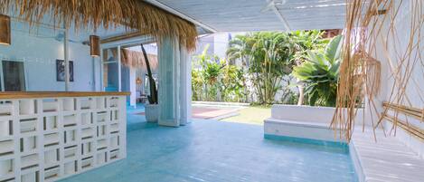 Un lobby moderno con mostrador de recepción, zona de piscina y exuberantes plantas de interior.